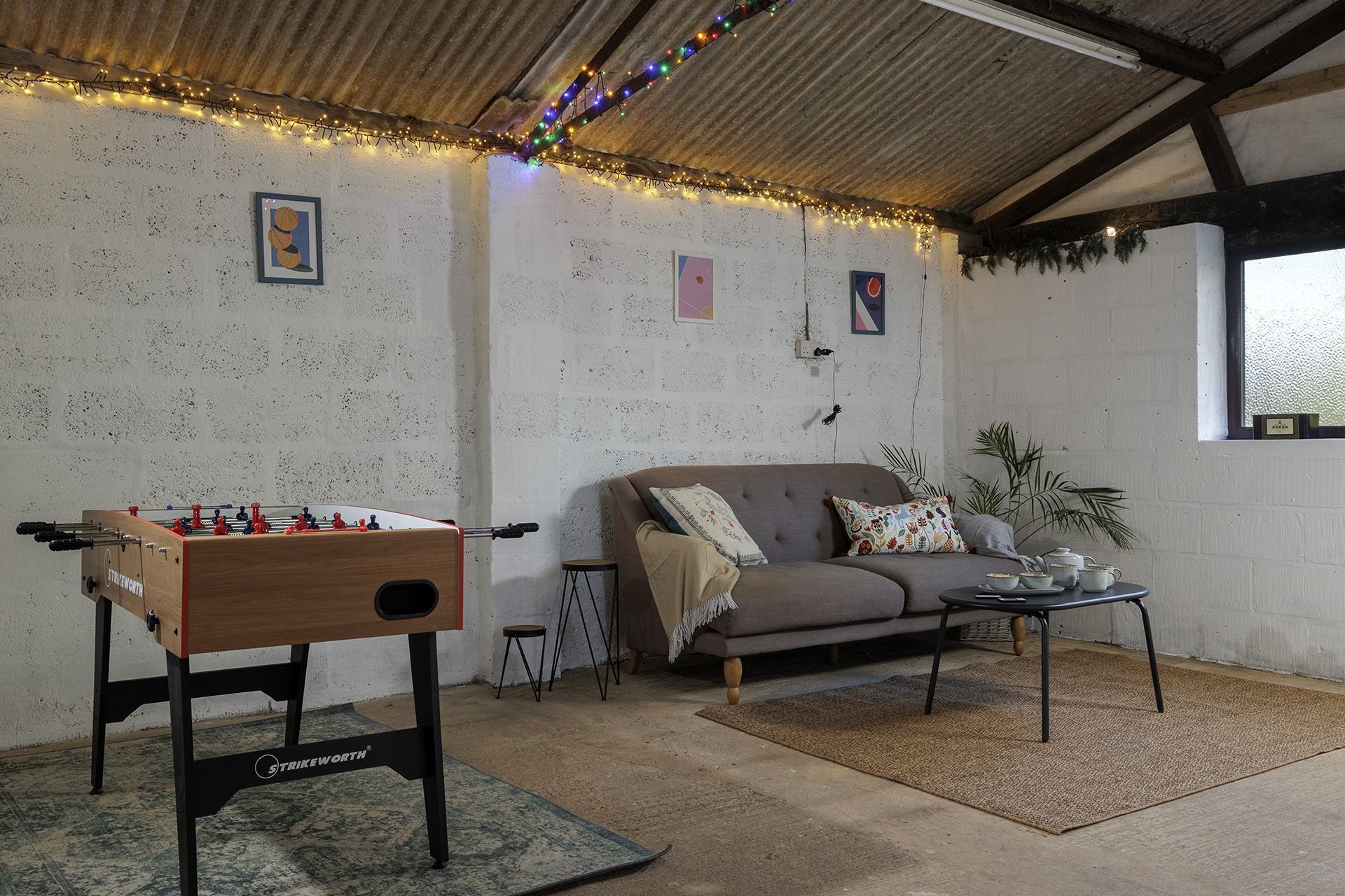 Una habitación acogedora con mesa de futbolín, sofá y una pequeña mesa con tazas y platitos.