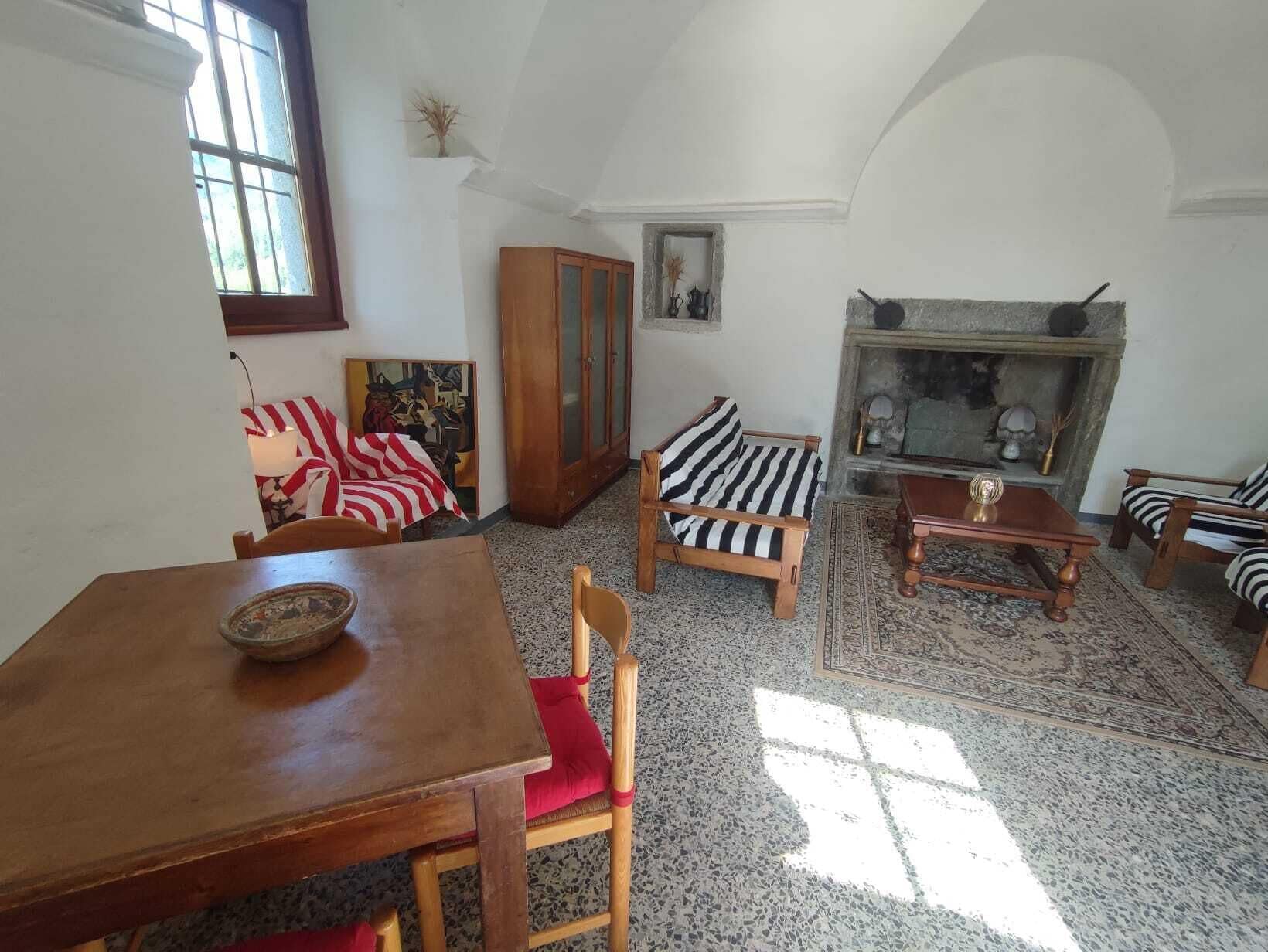 Ein gemütliches Wohnzimmer mit einem Holzesstisch, einem gestreiften Sofa und einem Kamin.