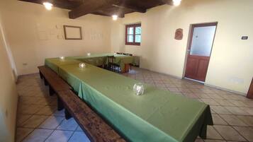A dining area with a long table covered in green tablecloths, benches along the sides, and a wooden ceiling.