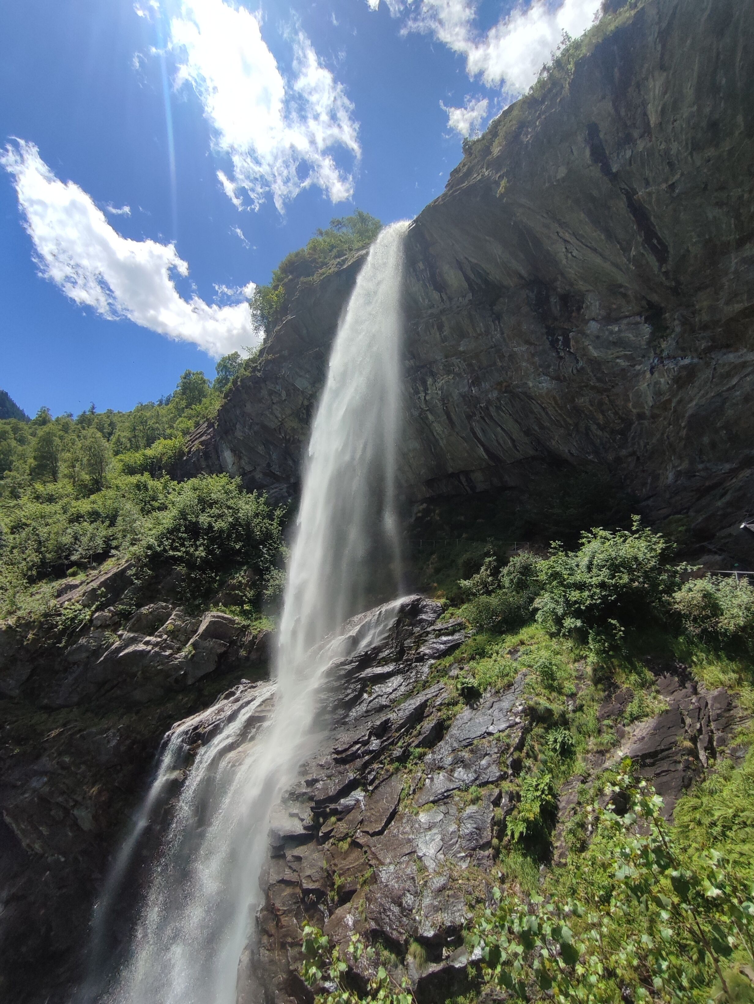 Ein Wasserfall stürzt über eine felsige Klippe, umgeben von üppigem Grün.