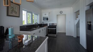 A modern kitchen with white cabinetry, a black granite countertop, and stainless steel appliances. -  Villa Lilia - 3 Bedroom Piton & Ocean View  in  Choiseul /Soufriere Area (Choiseul)