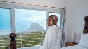A hotel room with a large window offering a view of a mountain and greenery. -  Villa Lilia - 3 Bedroom Piton & Ocean View  in  Choiseul /Soufriere Area (Choiseul)