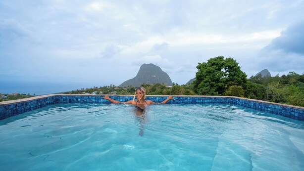 A swimming pool with clear blue water, surrounded by lush greenery and a mountainous backdrop. -  Villa Lilia - 3 Bedroom Piton & Ocean View  in  Choiseul /Soufriere Area (Choiseul)