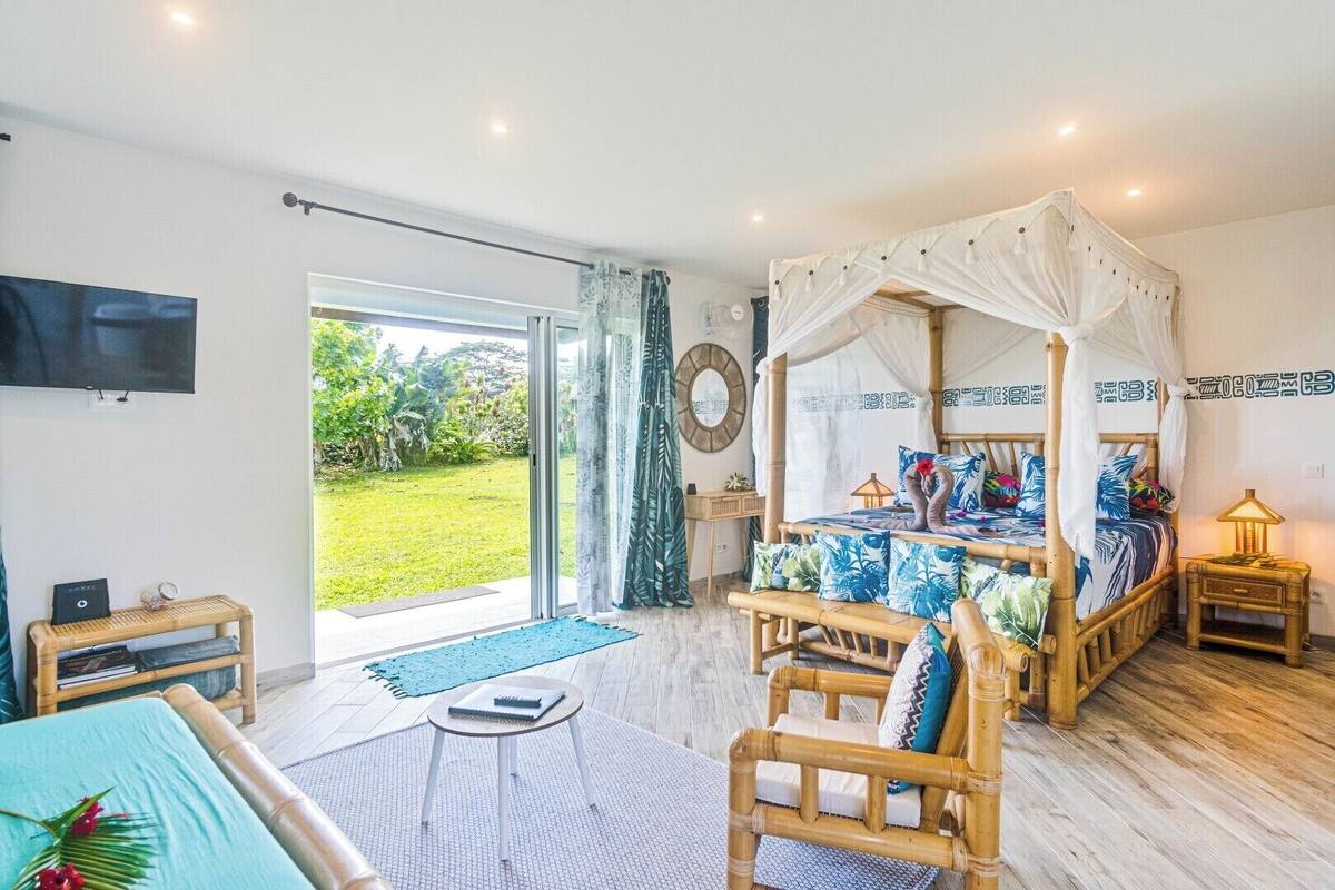 A room with a bed, a desk, a chair, a TV, and a view of the outdoors.