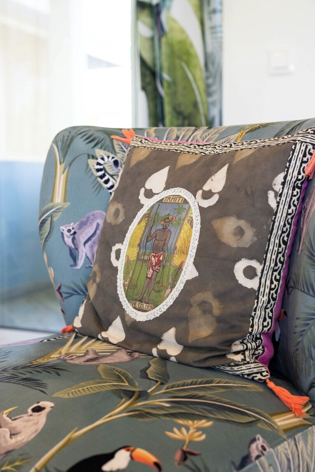 A sofa with a patterned cushion featuring a tropical design, including birds and foliage.