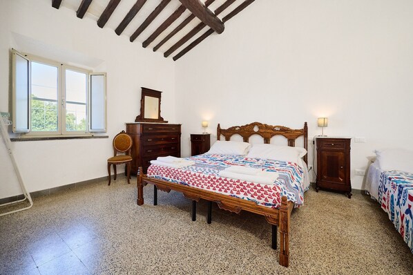 A bedroom with a wooden bed, a dresser, a chair, and a window.