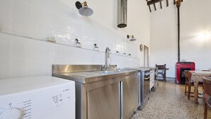 A kitchen with a stainless steel sink, a washing machine, and a red appliance on the right. - Room 'Camera 1 - Del Ponti' with Shared Garden and Wi-Fi (Casa Paduletto)