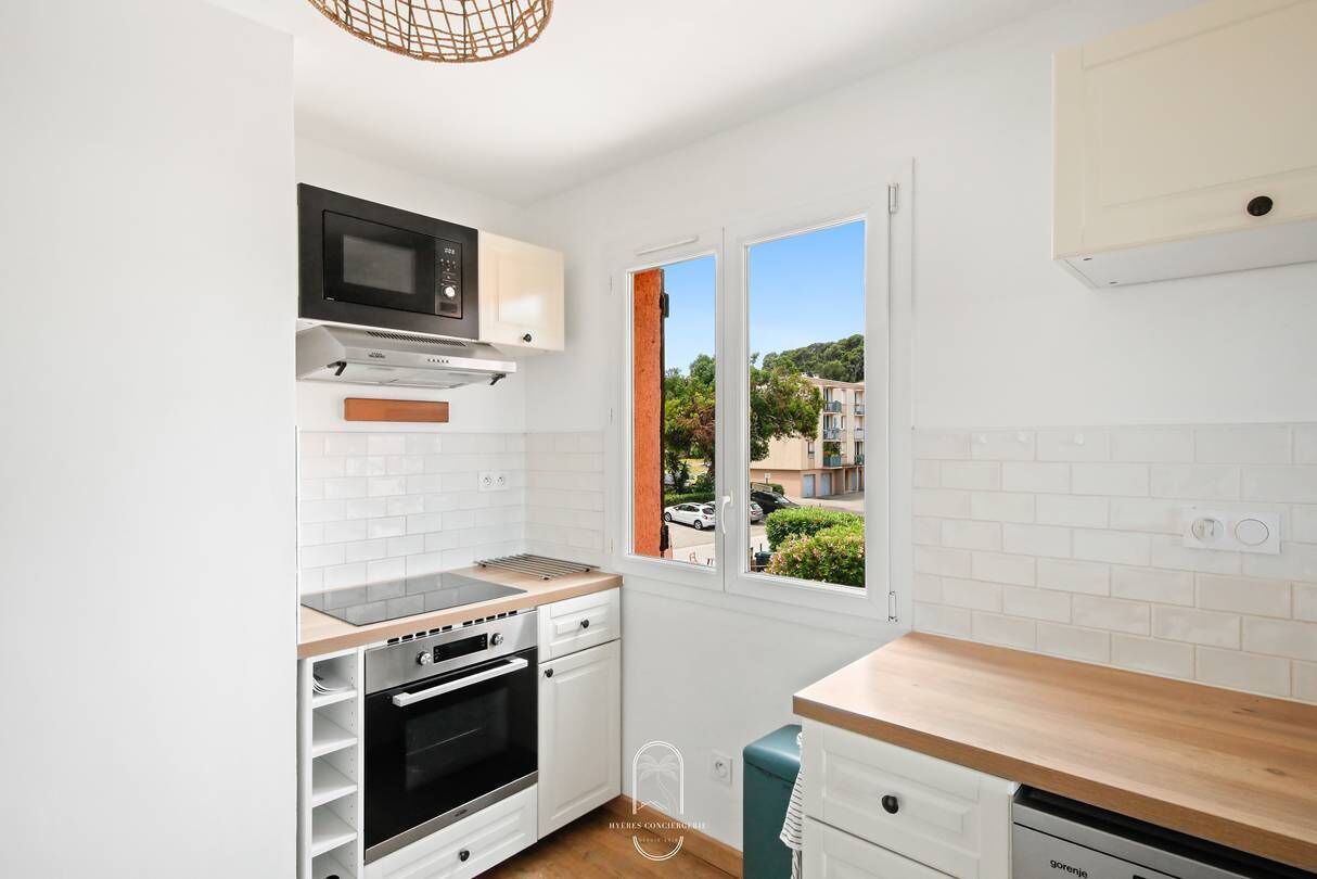 Une cuisine compacte avec des meubles blancs, un four à micro-ondes, une cuisinière et un lave-vaisselle.