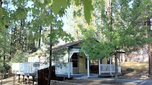 A cabin with a porch and a deck, surrounded by trees. - Sugar Bear (Big Bear City)
