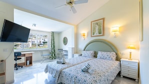 A bedroom with two beds, a desk, a chair, and a TV. - Townhouse Cortijos de La Hidalga (Benalmádena)