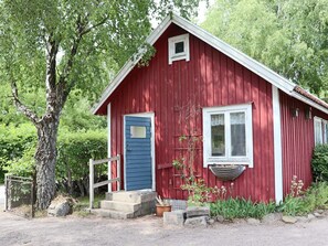 A red wooden building with a blue door, a small window, and steps leading to the entrance. - 4 Person Holiday Home in Steninge (Steninge)