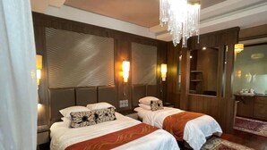 Hotellihuone, jossa on kaksi sänkyä, kattokruunu ja punakuvioinen matto.