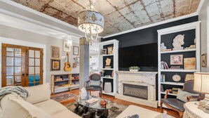 A spacious living room with a fireplace, a chandelier, and a bookshelf filled with books and decorative items. - Family & Friends - Fun In Franklin (Franklin)