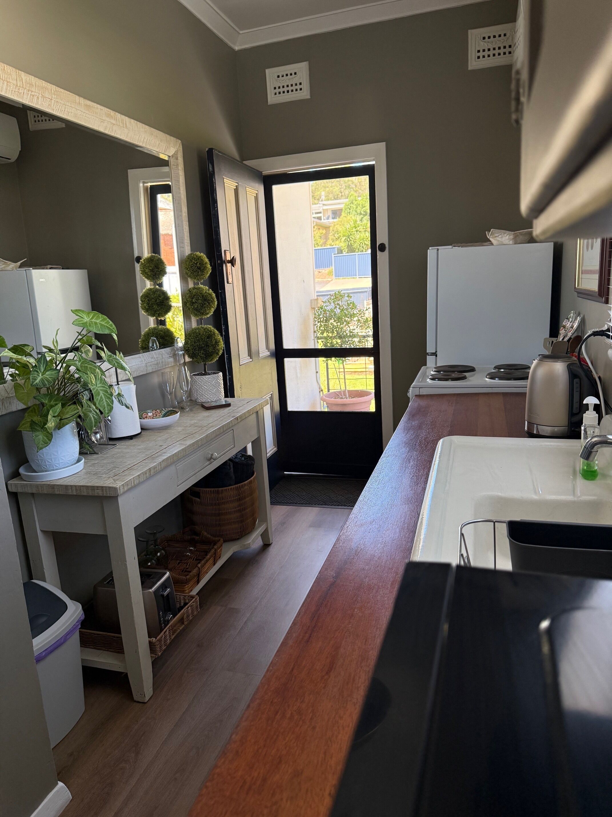 Cocina compacta con refrigerador, estufa, pileta y una planta en maceta.