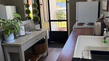 Cocina compacta con refrigerador, estufa, pileta y una planta en maceta.