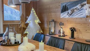 A cozy dining area with a wooden table, candles, and a Christmas tree with lights. - 1/2 Chalet: Alpine sweetness at Linga (CHATEL)