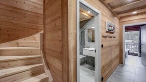 A wooden interior with a staircase leading to a bathroom with a shower and a sink. - 1/2 Chalet: Alpine sweetness at Linga (CHATEL)