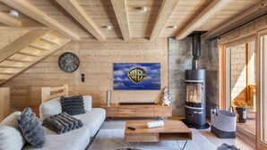 A cozy living room with a wooden ceiling, a large TV mounted on the wall, a fireplace, and comfortable seating. - 1/2 Chalet: Alpine sweetness at Linga (CHATEL)