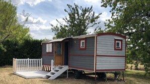 A mobile home with a porch and a ramp, surrounded by trees and a white fence. - QUIET ROULOTTE on land with swimming pool (Bernay-Saint-Martin)