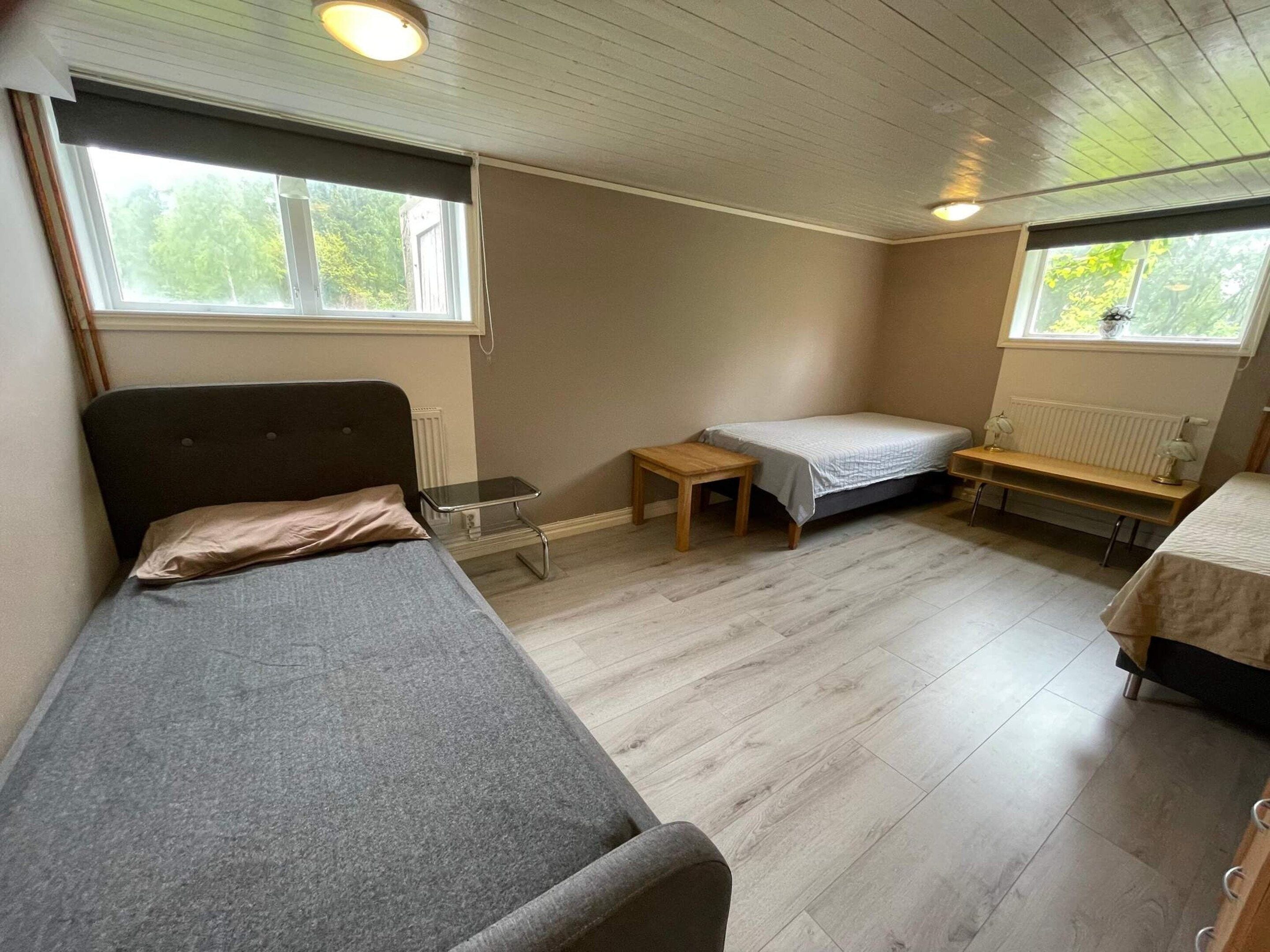 A compact room with a bed, a small table, a bench, and a radiator.