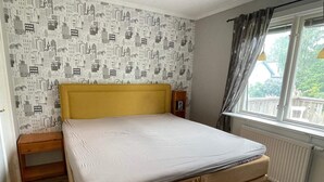 A bedroom with a bed, a nightstand, a window with curtains, and a radiator. - 4 Star Holiday Home in Karlskrona (Hasslö)