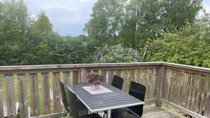 A wooden deck with a table and four chairs, surrounded by a wooden railing. - 4 Star Holiday Home in Karlskrona (Hasslö)