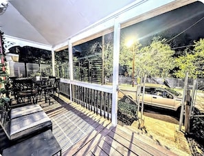 A covered outdoor area with a wooden deck, metal railing, and a car parked outside. - "Atlanta Gem with Fun Backyard Activities & Cozy Lounge"! (Atlanta)