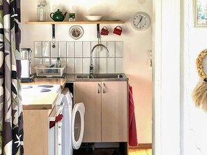 A compact kitchen with a washing machine, a sink, and a clock on the wall. - 2 Person Holiday Home in Odeshog (Odeshog)