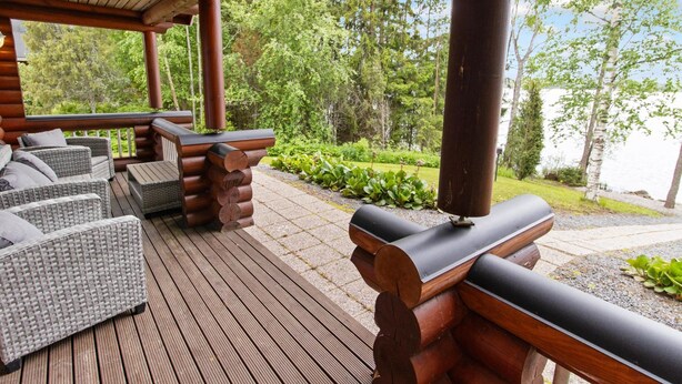 Eine Holzterrasse mit Korbmöbeln und Grillplatz.