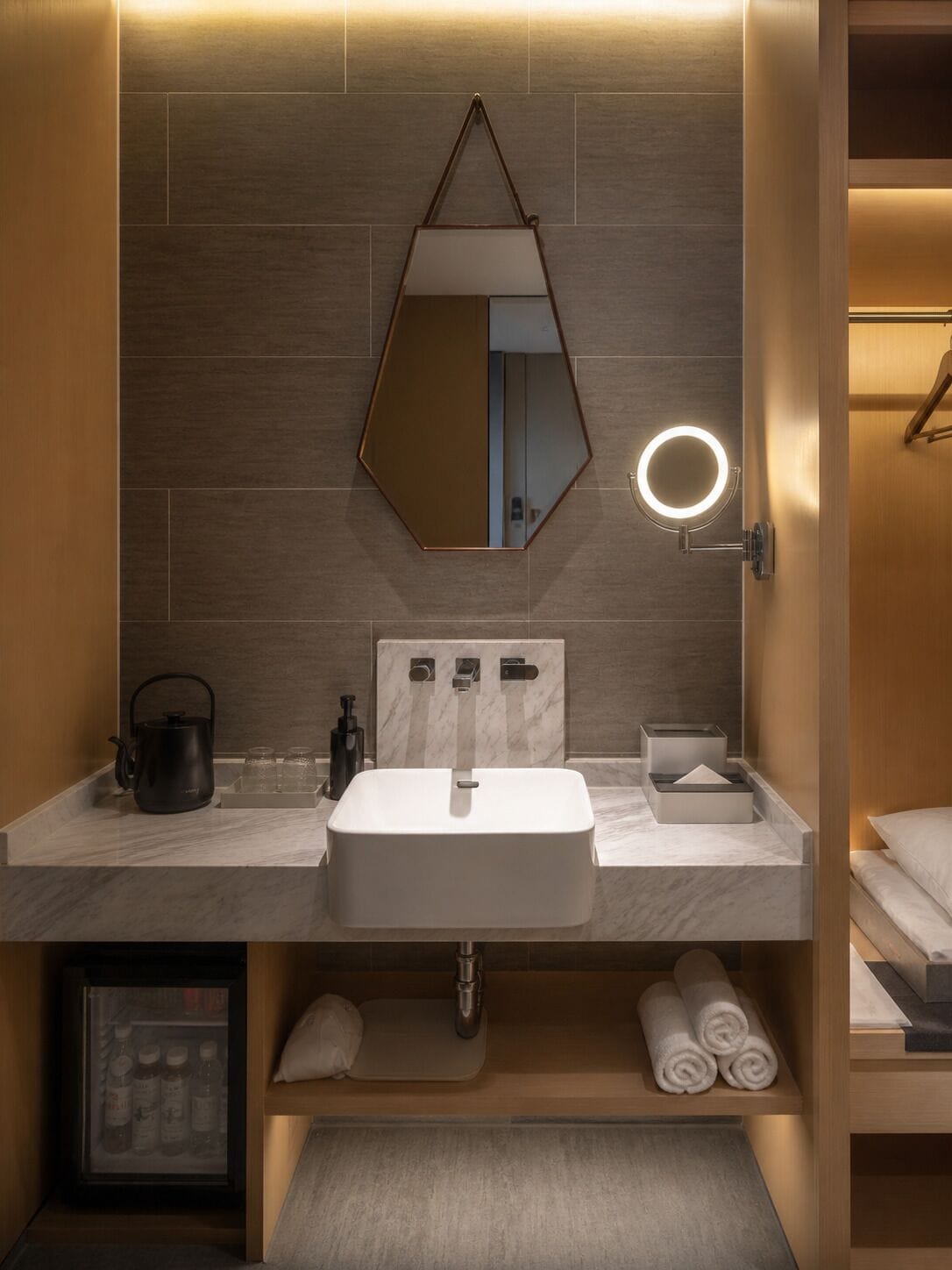 A modern bathroom with a large mirror, a sink, and a towel rack.