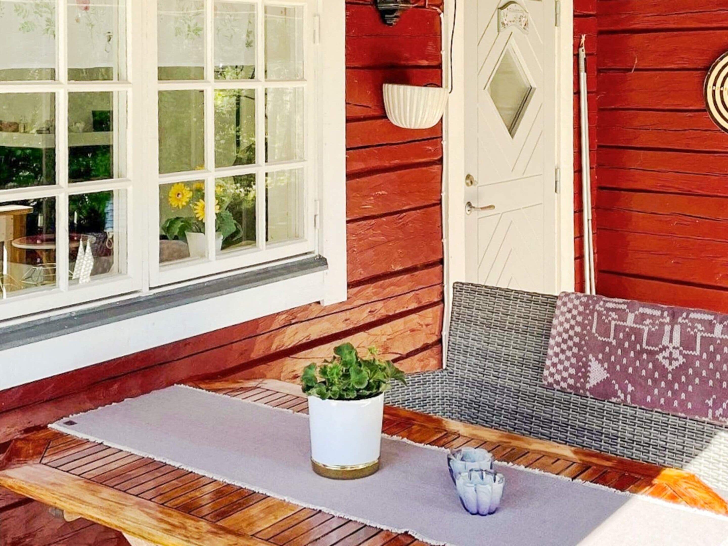 A wooden porch with a bench, a potted plant, and a door with a decorative handle.