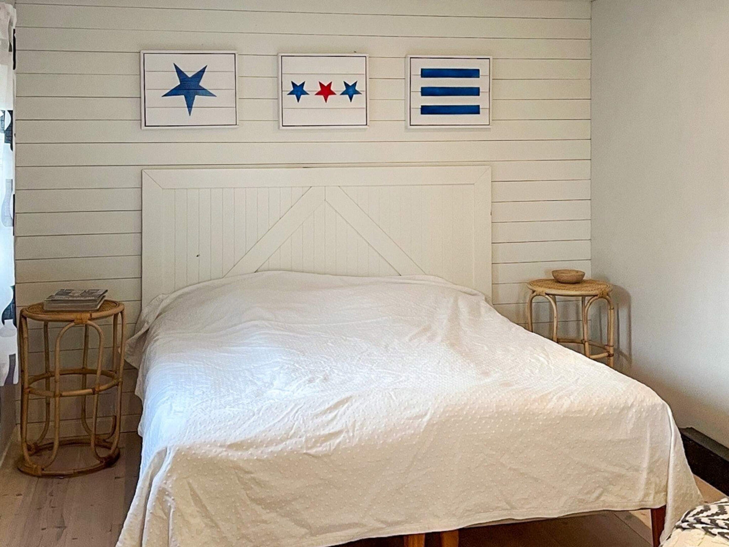 Un dormitorio con una cama, dos mesitas de noche y adornos en la pared.