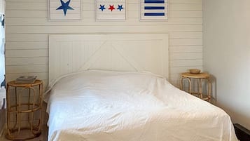 Un dormitorio con una cama, dos mesitas de noche y adornos en la pared.