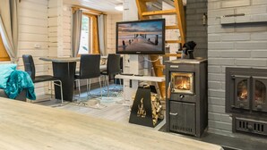 Un salon chaleureux avec une cheminée, un téléviseur et un espace en mezzanine accessible par une échelle en bois.