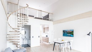 A modern apartment with a spiral staircase, a dining area, and a living room with a sofa.