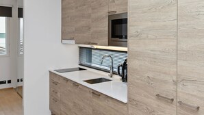 A modern kitchen with a built-in microwave, a sink, and a coffee maker.