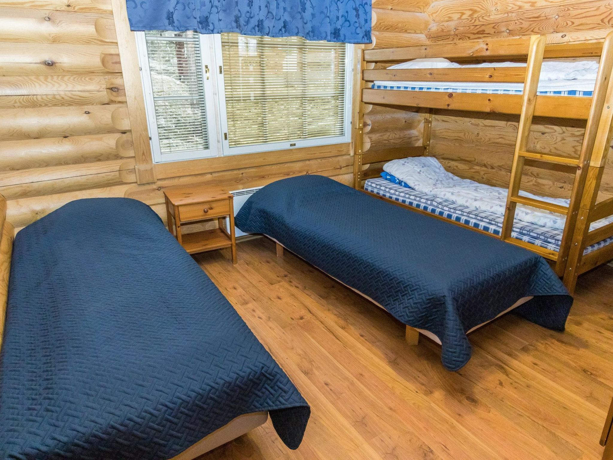 Habitación tipo cabaña con dos literas, un escritorio de madera y una ventana con persianas.
