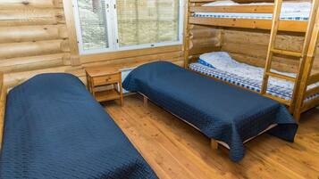 Habitación tipo cabaña con dos literas, un escritorio de madera y una ventana con persianas.