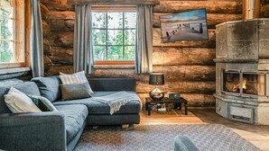 A log cabin interior with a sofa, a fireplace, a window with curtains, and a painting on the wall. - Rukan pilvimaja by Interhome (Kuusamo)