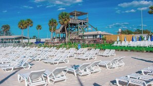 A beach with rows of white sun loungers, a wooden observation tower, and a building with a covered area. - Boat, Kayak & Relax: Stunning Waterfront Home w/ Sunsets and Direct Gulf Access (Hernando Beach)