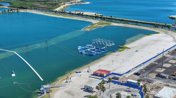 An aerial view of a coastal area with a marina, sandy beach, and a small building.