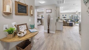 A modern interior with a wooden reception desk, framed welcome signs, and a cozy seating area in the background. - Boat, Kayak & Relax: Stunning Waterfront Home w/ Sunsets and Direct Gulf Access (Hernando Beach)