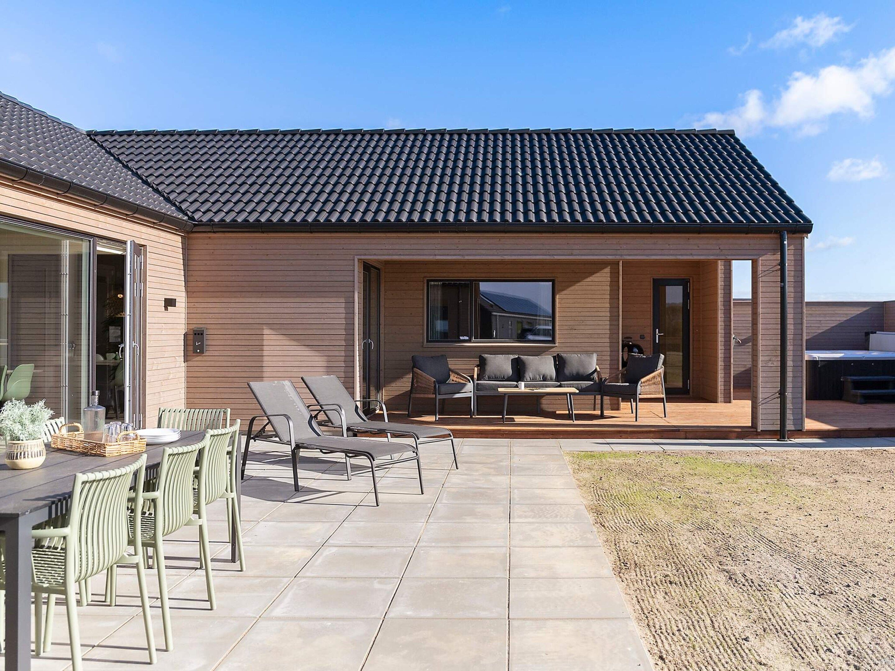 A modern house with a patio area featuring outdoor furniture and a dining table.