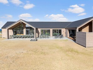 A modern building with a covered patio area, large windows, and outdoor seating. - 5 Star Holiday Home in Bogense (Bogense)