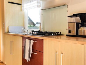 A kitchen with a gas stove, a coffee maker, and a window with a view of houses.