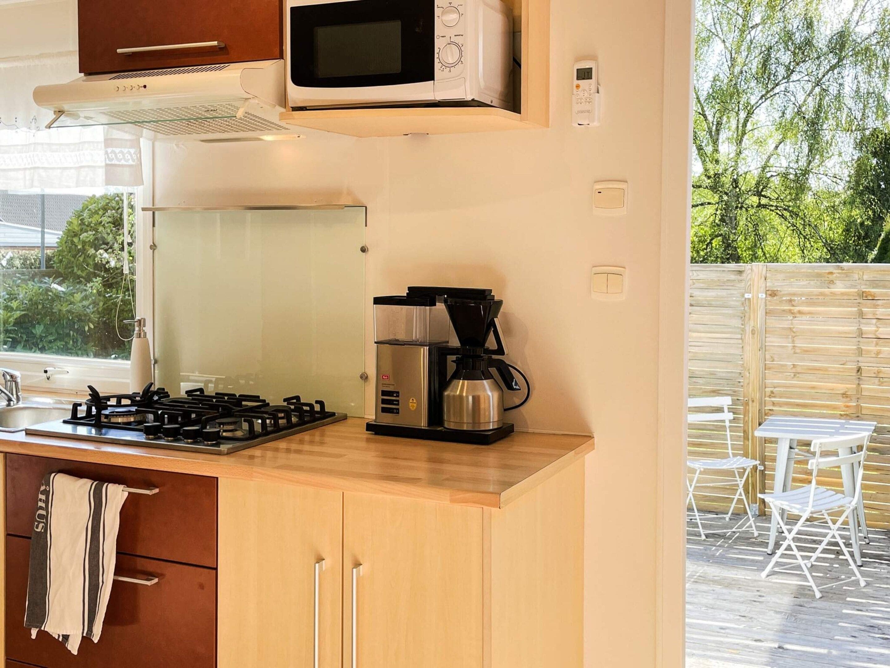Cozinha compacta com fogão a gás, cafeteira e micro-ondas.