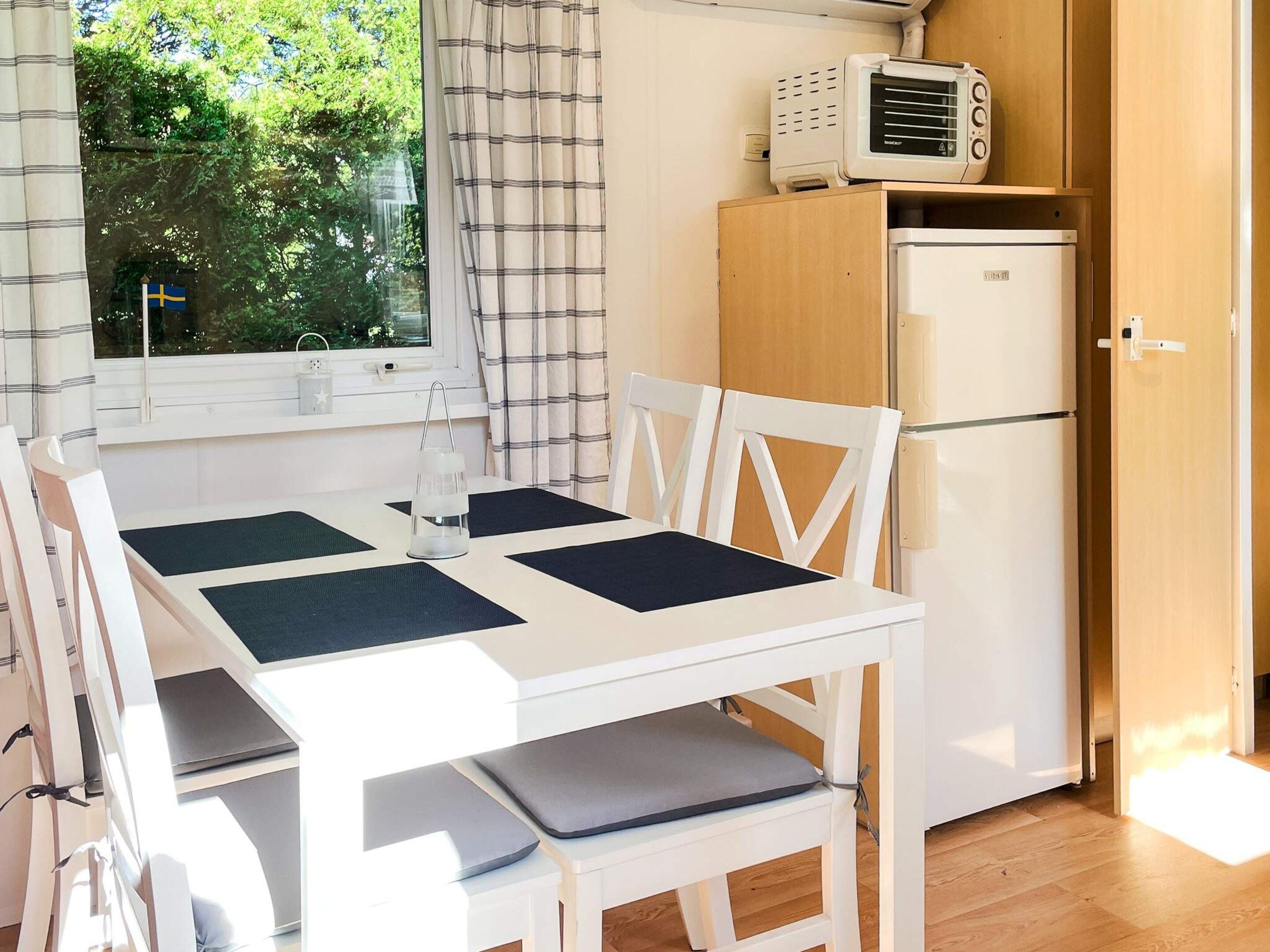 A compact kitchen with a white table, two chairs, a microwave, and a refrigerator.
