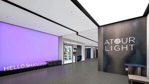 A modern hotel corridor with a 'HELLO SHANGHAI' sign, vending machines, and a 'TOUR LIGHT' sign. - Atour Light Hotel on the Bund Nanjing Road (Shanghái)