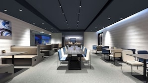 A modern conference room with a long table and chairs, a kitchen area in the background, and a seating area with sofas and tables. - Atour Light Hotel on the Bund Nanjing Road (Shanghái)