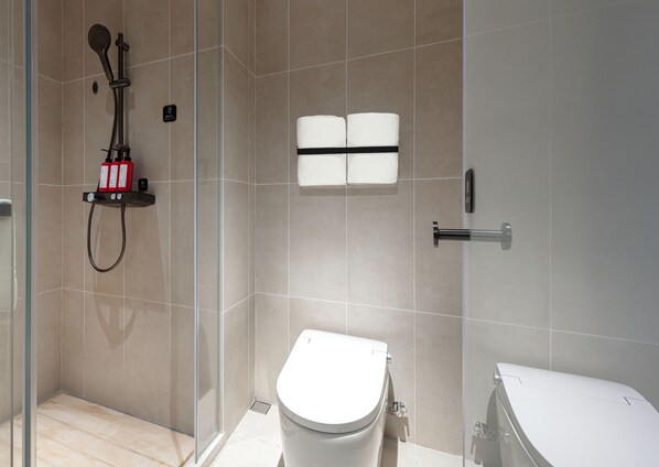 Un baño moderno con cabina de ducha de vidrio, inodoro y bidé.